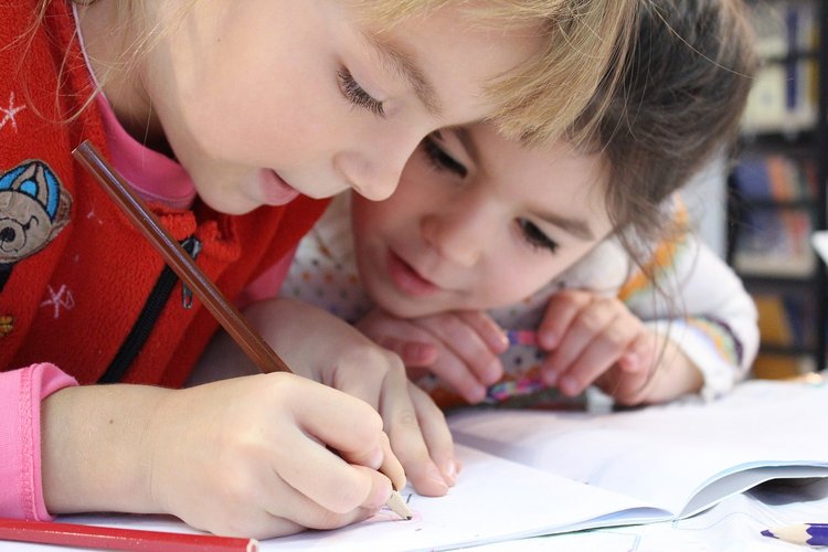 Enfants Un enfant tenant un crayon pour dessiner et un autre qui le regarde faire